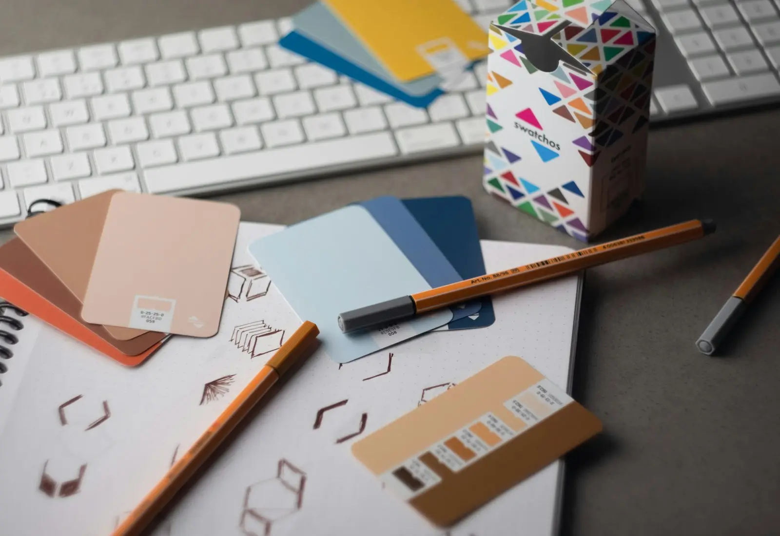 Mesa de diseño gráfico con muestras de color, lápices y teclado