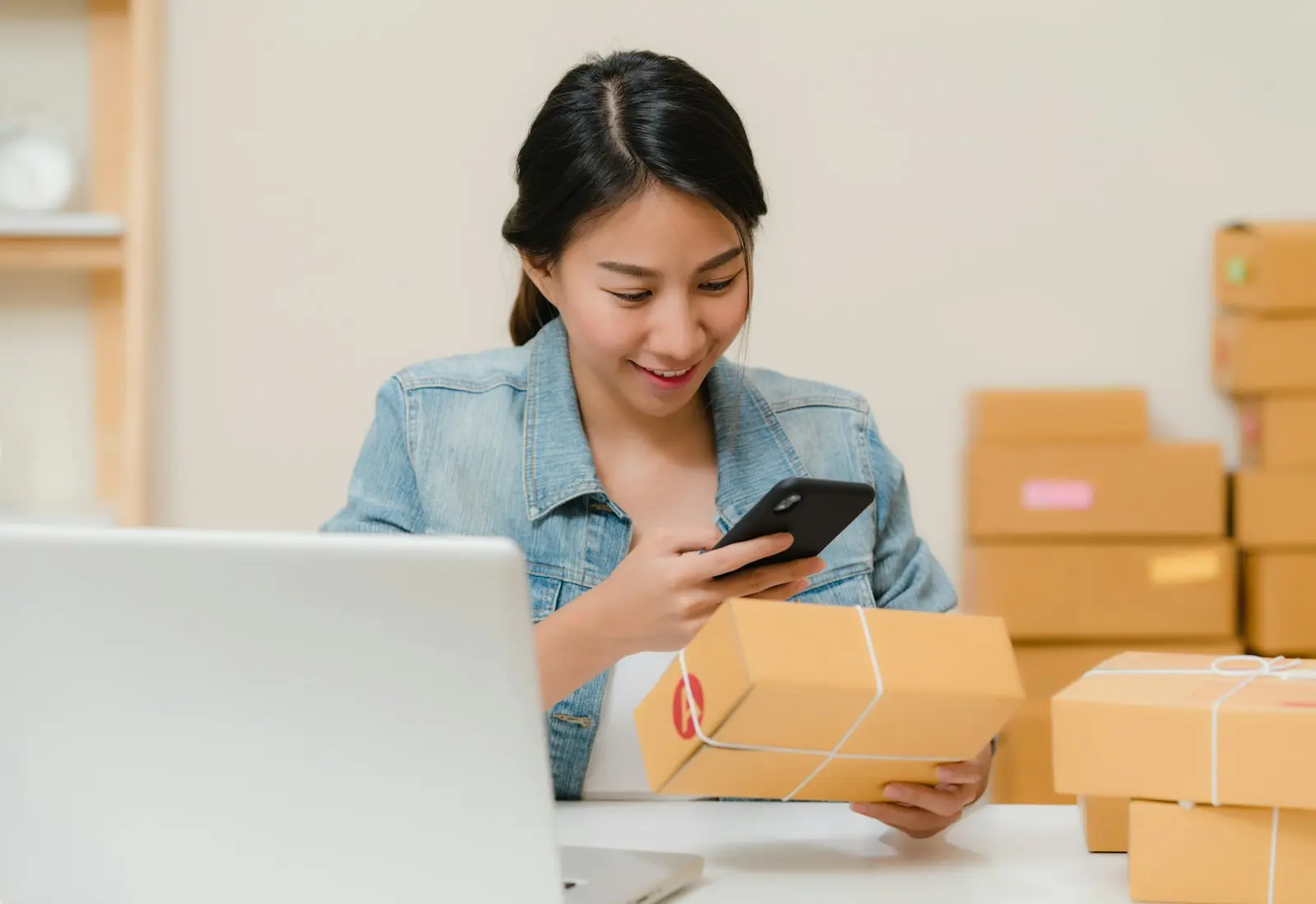 Imagen editorial de una emprendedora preparando pedidos junto al portátil